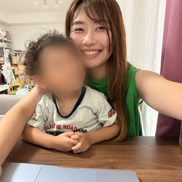 子どもを抱っこしてお仕事するかほさん(お子さんの顔はぼかし)